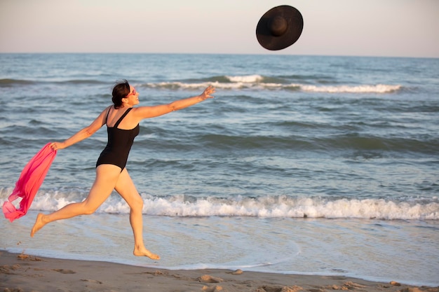 A woman runs along the shore for a hat Holidays at sea