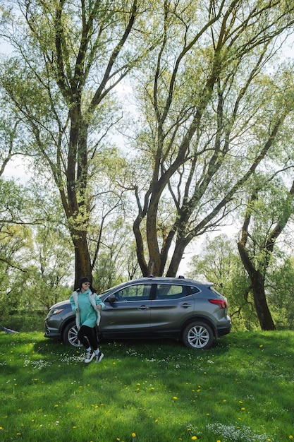 a woman runs from a parked car on a green lawn in nature