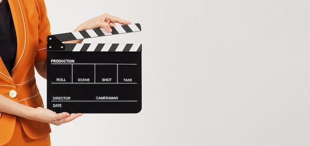 The woman's body part hold a Black Clapperboard or movie Clapper board and she wears a yellow yellow suit on white background