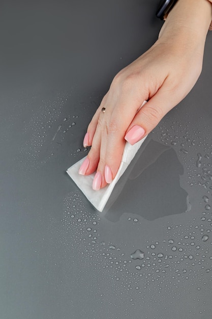 Woman's hand cleaning the table surface with wet wipes