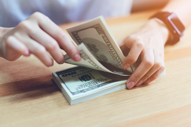 Woman's hand counting money 100 dollars. The concept of spending by cash.