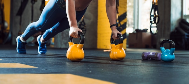 Woman's hand doing push ups on kettle ball in gym