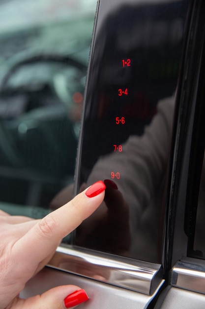 Photo a woman's hand enters the secret code for opening the car door on the touch panel