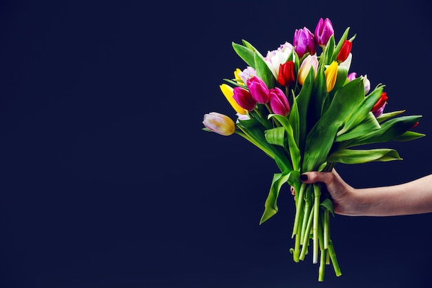 Woman's hand gives a bouquet of tulips