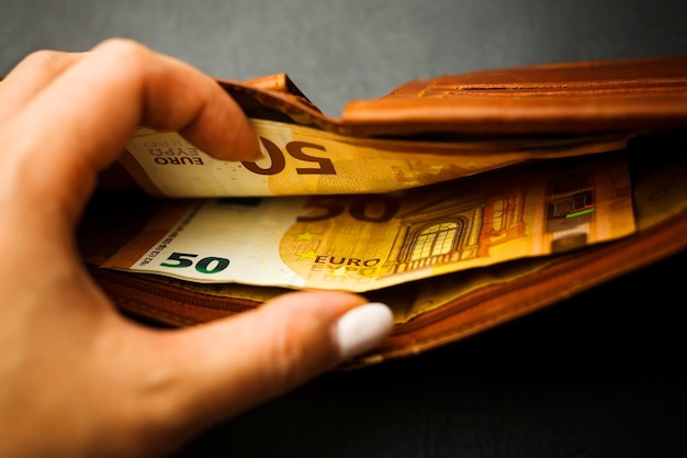 Woman's hand hand takes out banknotes from a brown wallet