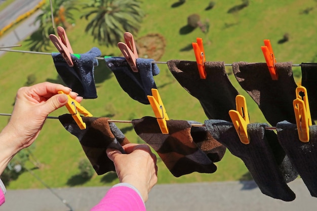 Woman's hand hanging socks on clothesline with clothespin on the upper floor