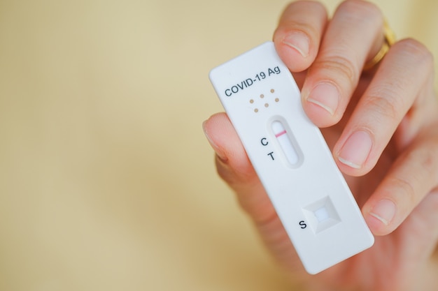 Woman's hand holding antigen test kit for covid 19 with yellow background, Selective focus.