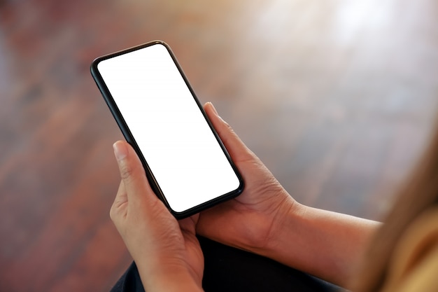  a woman's hand holding black mobile phone with blank white desktop screen