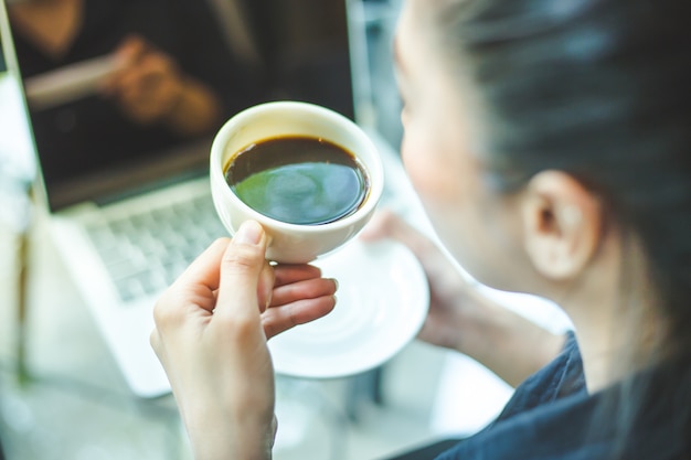 Woman's hand holding a cup of hot coffee on the office desk