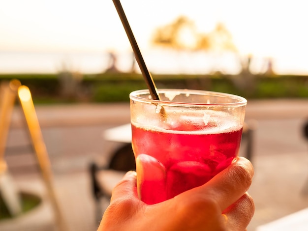 Woman's hand holding a glass of sangria against the sunset