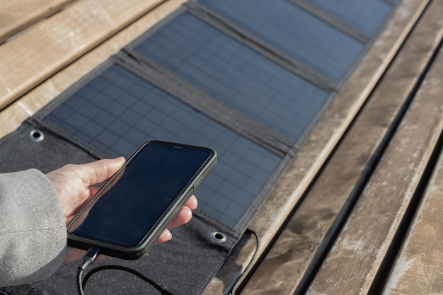 Woman's hand holding a phone connected to a solar panel