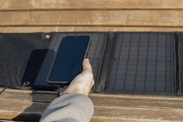 Woman's hand holding a phone connected to a solar panel