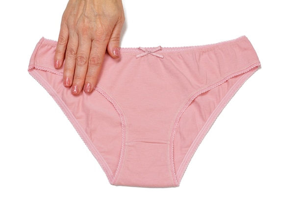 Woman's hand holding pink cotton panties on white isolated background. Woman underwear set. Top view.