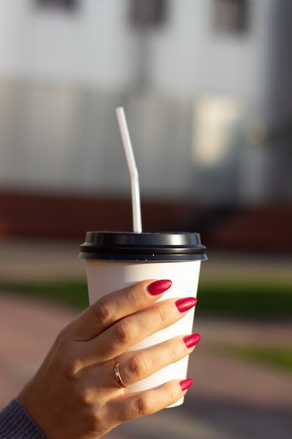 A woman's hand holding a white coffee Cup.