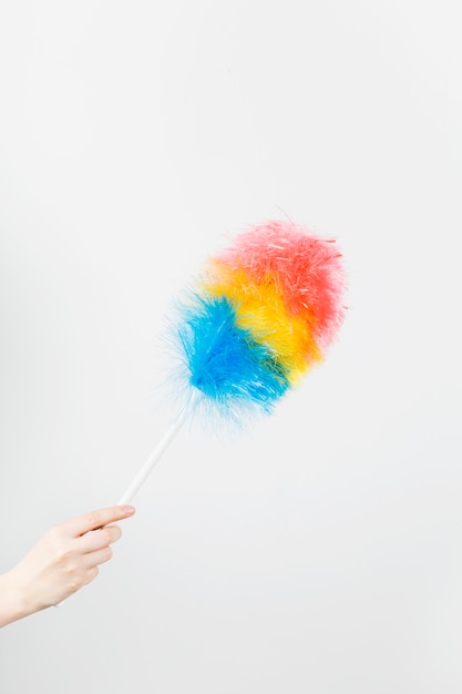 Woman's hand holds brush to clean dust on grey wall