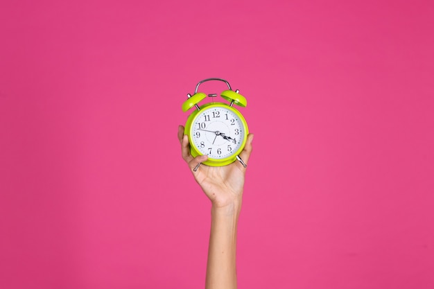 Woman's hand holds green alarm clock