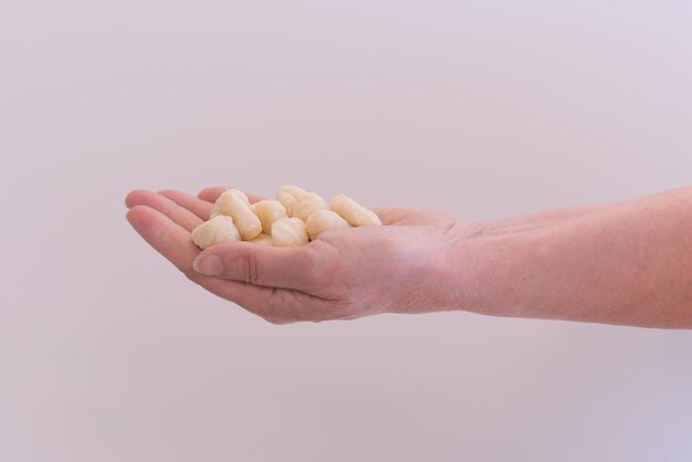 The woman's hand holds a heap of Italian gnocchi on a white background Cheese Cuisine Traditional Recipe Group Round Row Making Pasta Raw Hand Homemade Italy