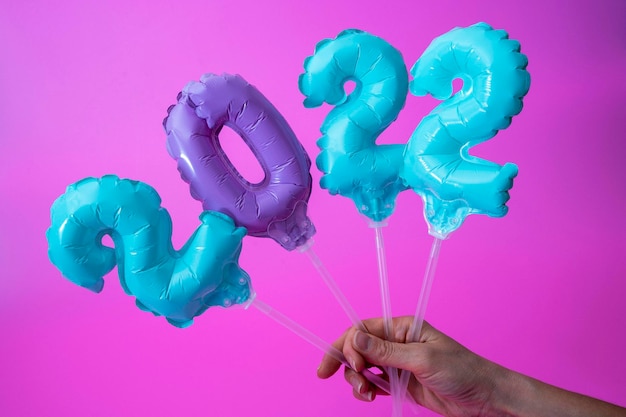 A woman's hand holds inflatable figures with the numbers 2022 on a purple background, inflatable balloons 2022, New Year's concept and Christmas decorations, greeting card, greeting