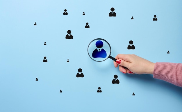 A woman's hand holds a magnifying glass and focuses on a leadership badge the concept of human resource management