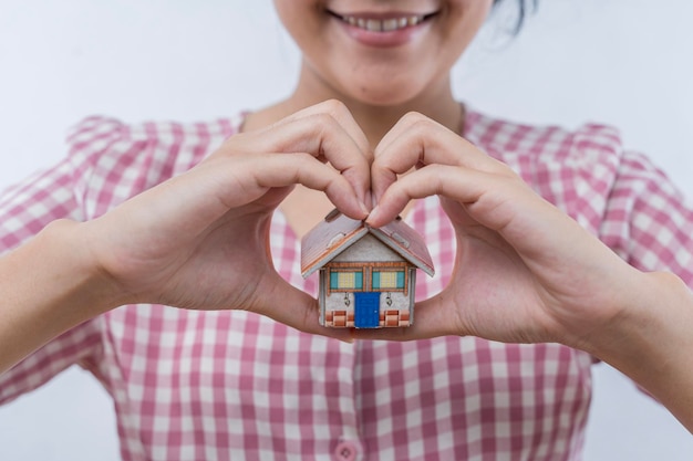 A woman's hand holds a mockup or miniature of a residential building Purchase and sale of real estate construction of a residential building