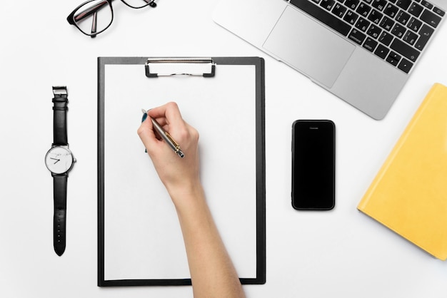 A woman's hand holds a pen and writes on a clean sheet of paper.