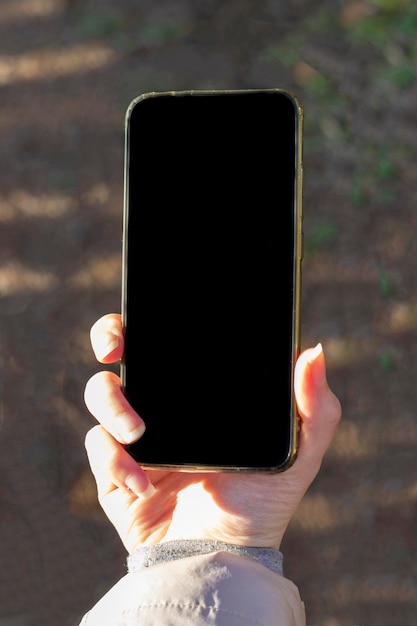 A woman's hand holds a phone with a black screen Phone in hand with a place to advertise