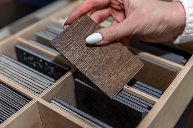 A woman's hand holds a sample of a wooden floor Design and decor in the interior construction and repair Closeup