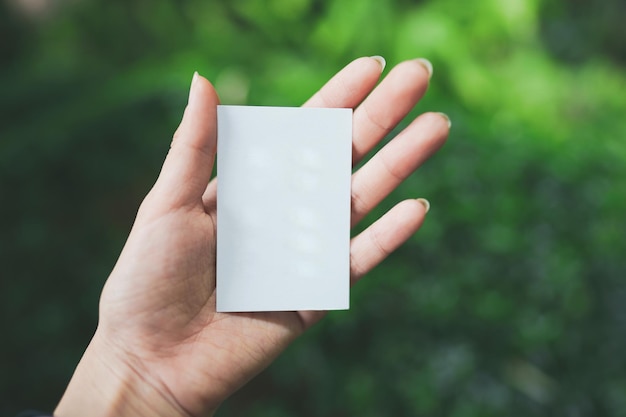 A woman's hand holds a small blank white paper with space for text