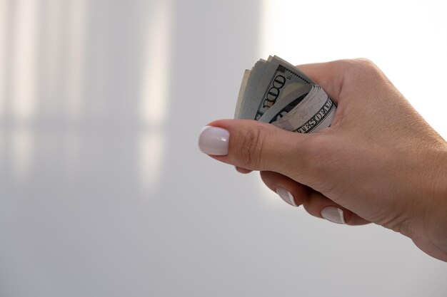 A woman's hand holds a stack of cash.