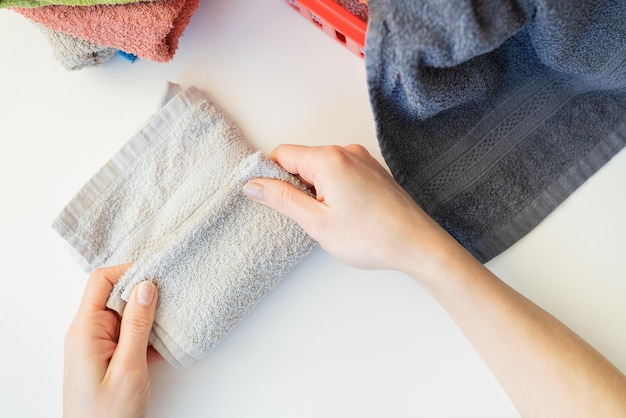 A woman's hand holds a terry towel from a clothes basket Towel after washing The girl folds the towel after washing folding clothes