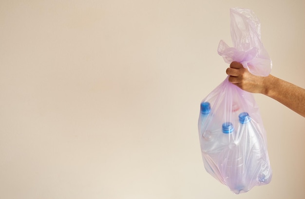 Woman's hand holds a trash bag with plastic bottles copy space for advertising