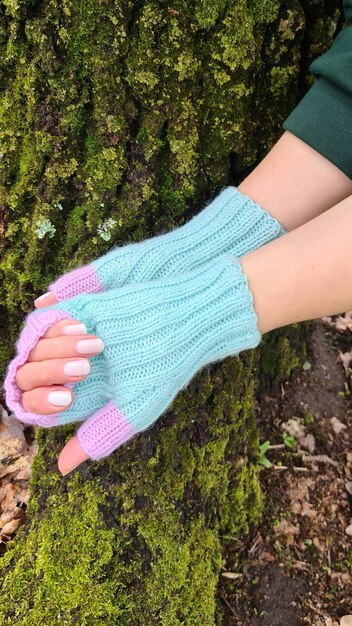 A woman's hand is holding a pair of blue knitted gloves.