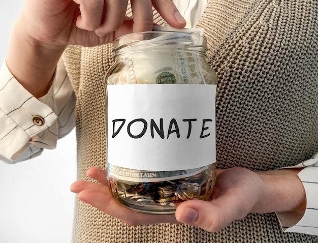 Woman's hand putting coin in black wallet with word Donate