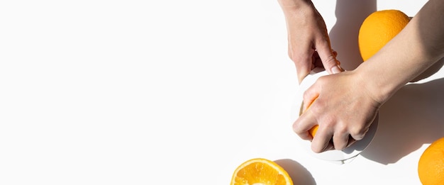 Woman's hand squeezes juice from an orange with a manual bowl on a white background Top view flat lay Banner