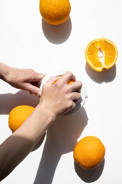 Woman's hand squeezes juice from an orange with a manual bowl on a white background Top view flat lay