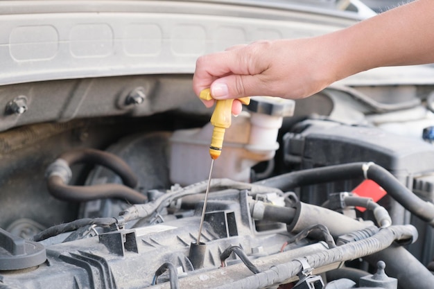 Woman's hand takes out a dipstick for oil from a car engine