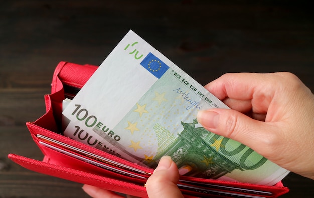 Woman's hand taking Euro banknotes from the red wallet