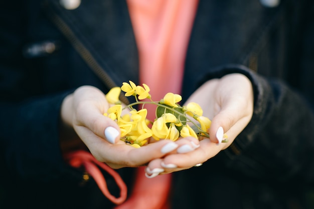 Woman's hand with a flower on sunny summer day.