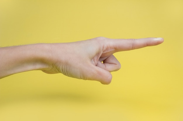 A woman's hand with an index finger on a yellow background.