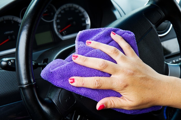 Woman's hand with microfiber cloth polishing wheel of a car