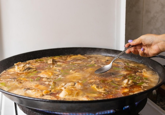 Woman's hand with spoon to taste Valencian Paella