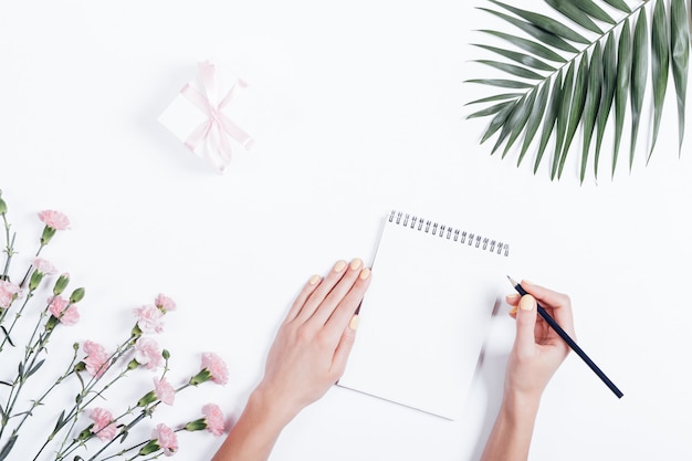 Woman's hand writing in a notebook at the desk, top view