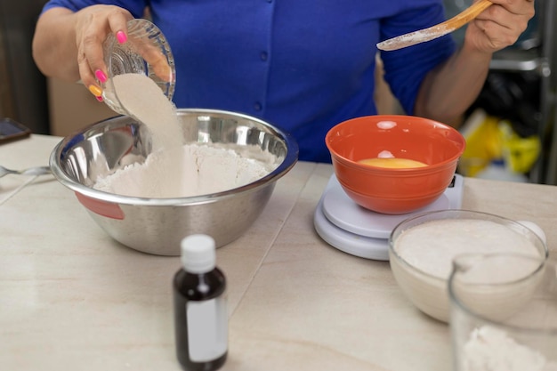 Woman's hands adding sugar to a bowl with flour to prepare bread