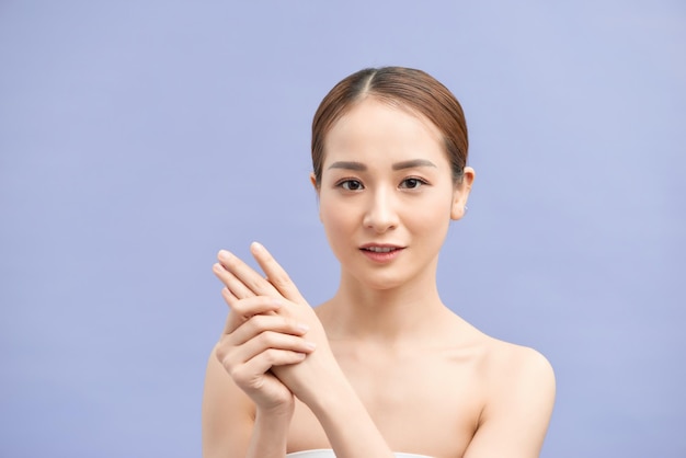 Woman's hands applying moisturizing handcream on violet