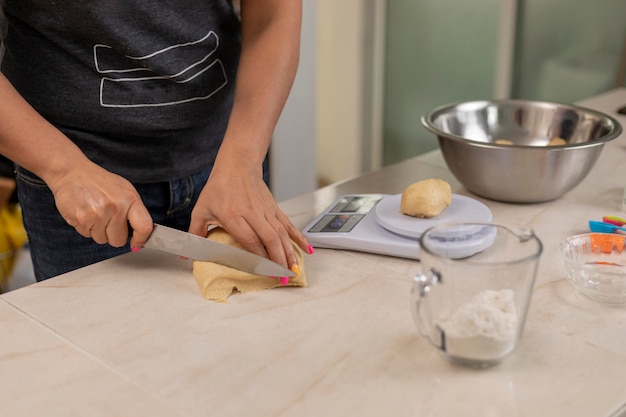 Woman's hands cutting dough to make bread to weigh on a scale