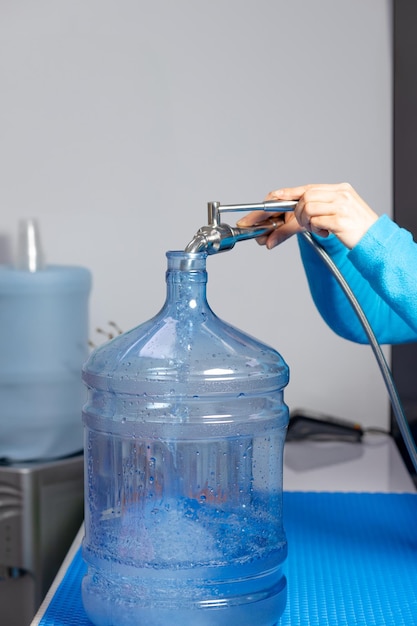 Woman's hands filling a gallon of clean water with a faucet