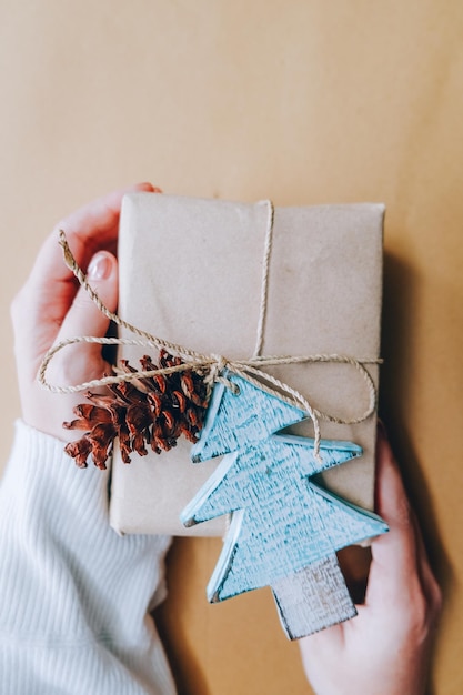 Woman's hands hold christmas or new year decorated gift hand made box Toned picture