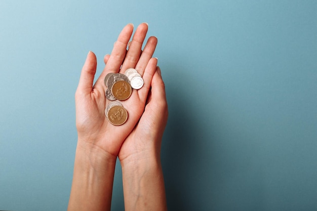 Woman's hands holding a heap of coins background top view with copy space