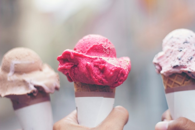 Woman's hands holding melting ice cream waffle cone in hands on summer light