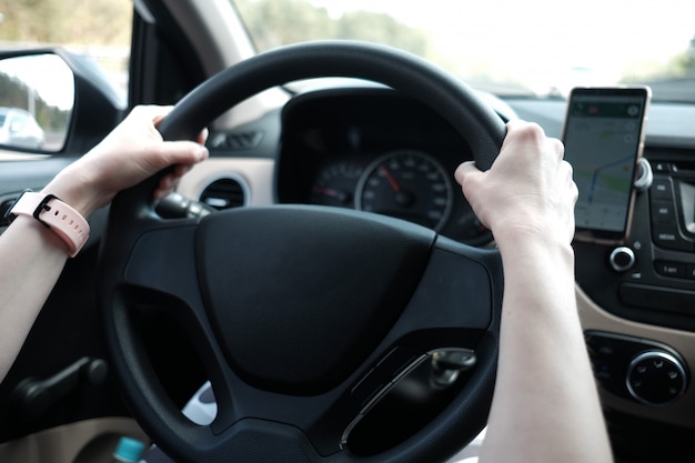 Woman's hands holding steering wheel while driving a car